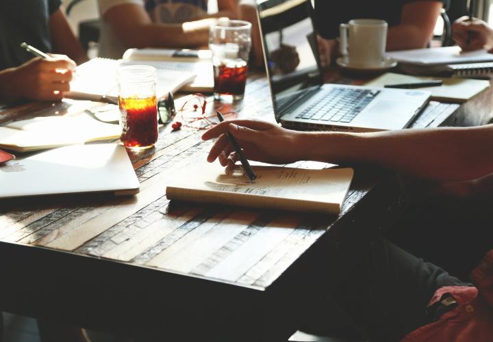 people writing at a coffeehouse table